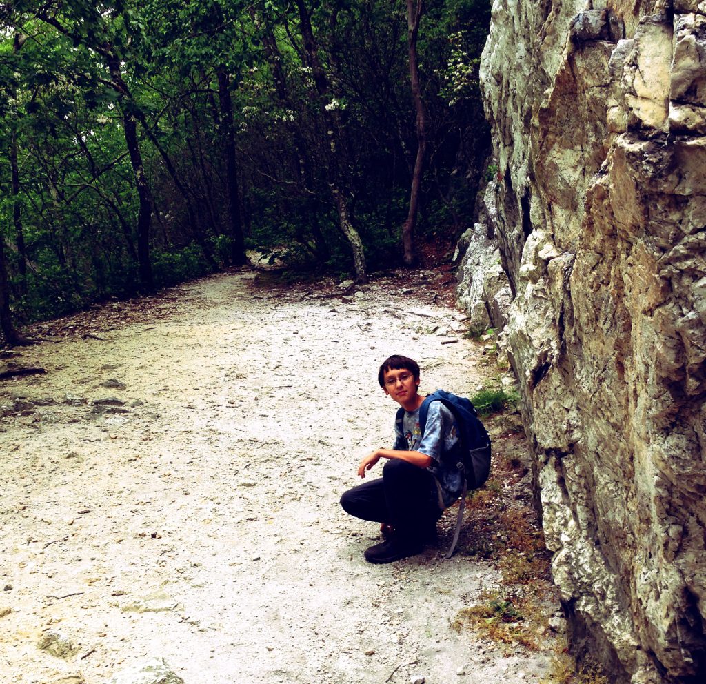 Ben pausing for a picture at the base of one of the rock walls on the hike.